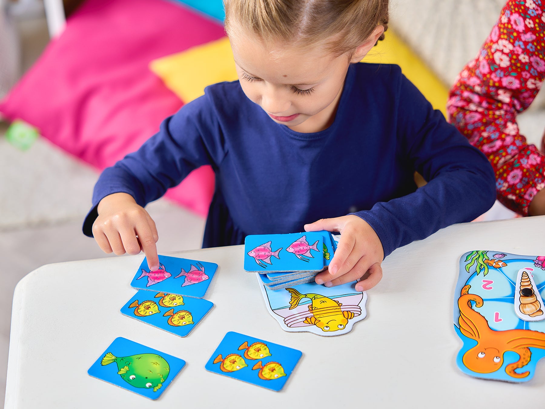 Child playing with educational cards featuring animals and letters on a table.