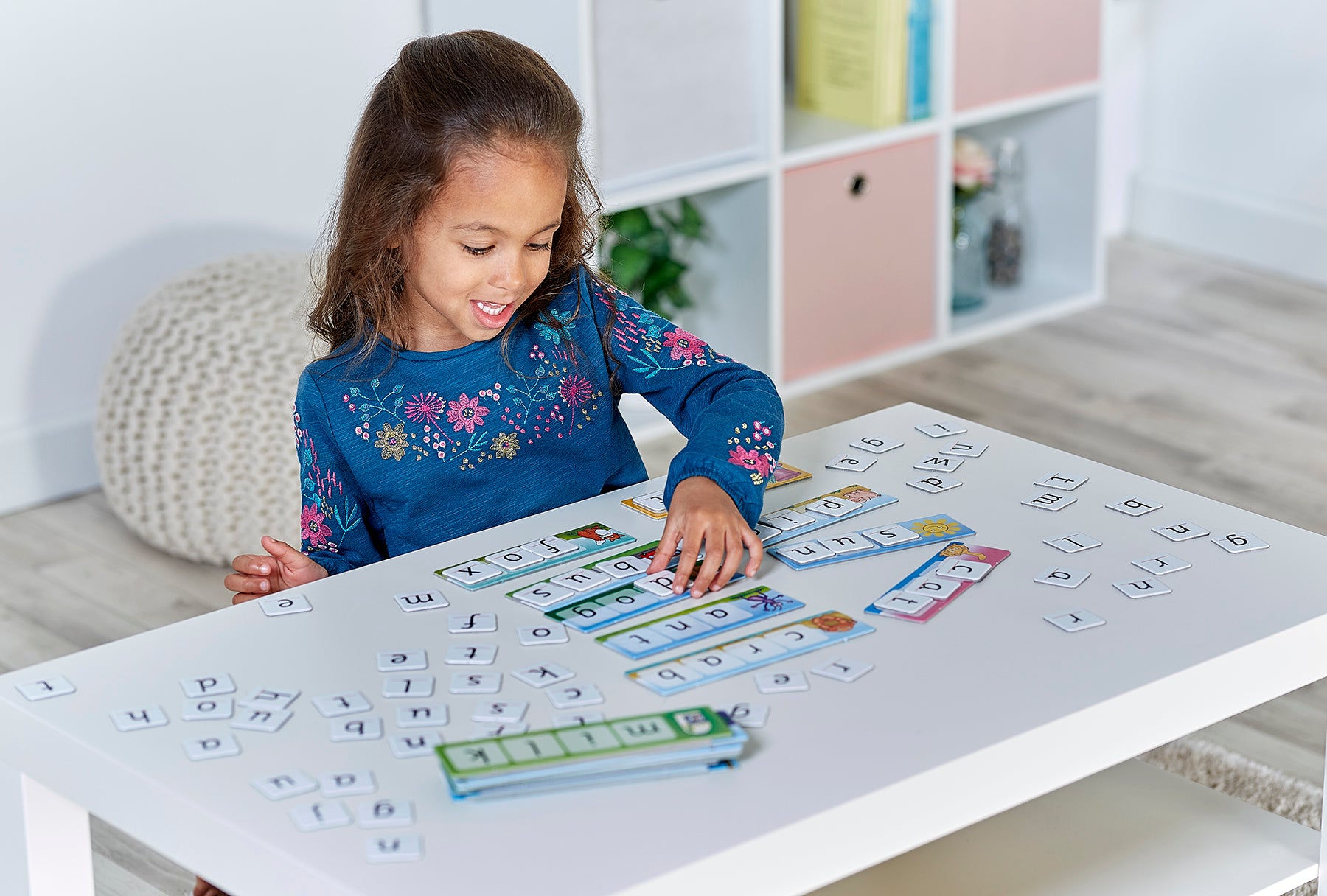 Child playing with educational toys on a table in a room with shelves and decor.