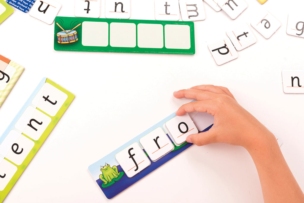 Hand placing letter tiles on a word strip with educational letters and numbers in the background