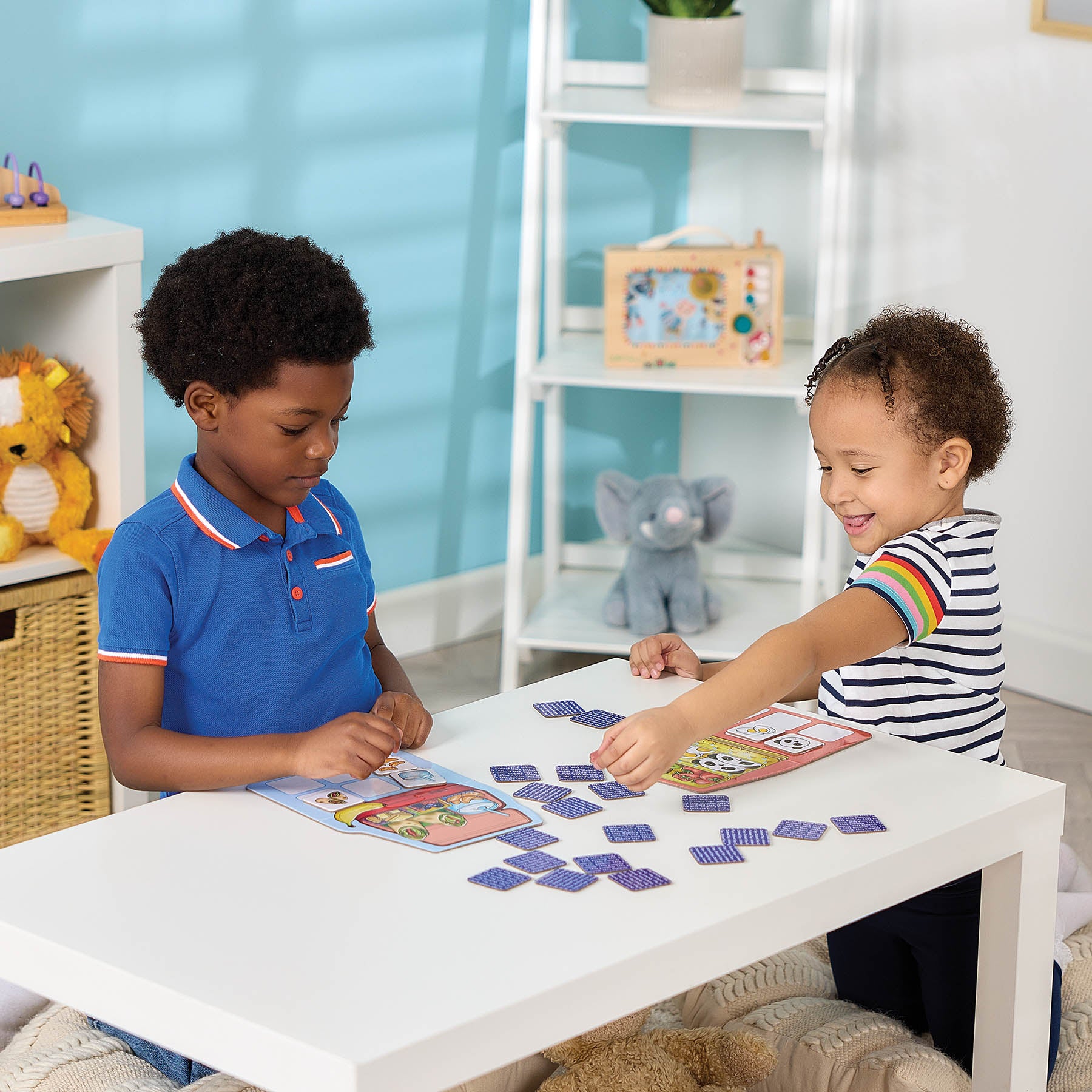 Two young children playing with a colorful educational math game on a white table in a bright, modern children's room.