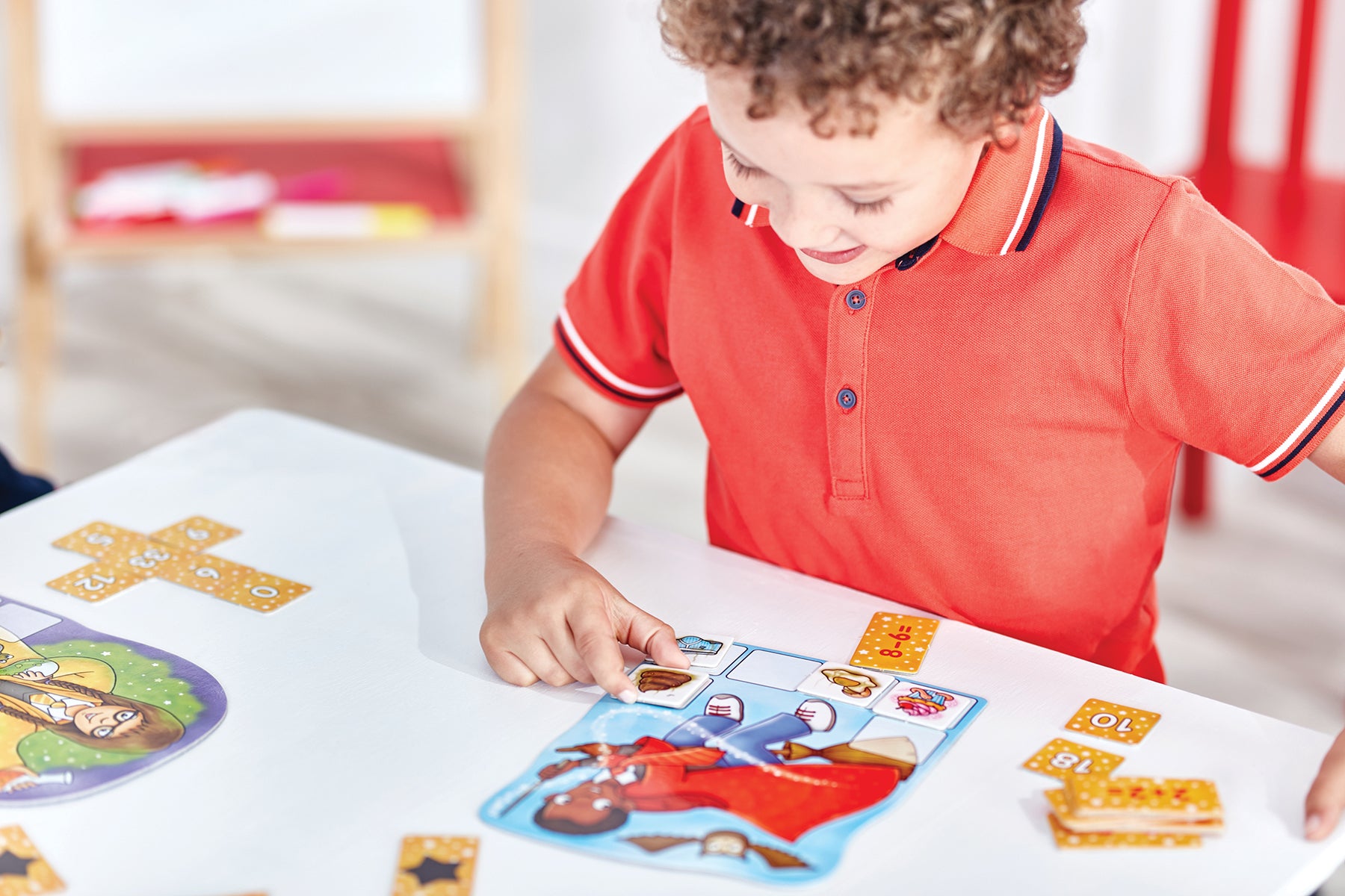 Child playing with educational cards at a table in a classroom setting
