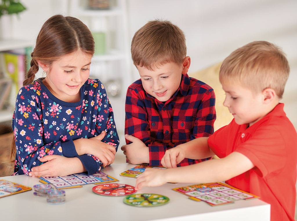 Three children playing a board game together on a table.