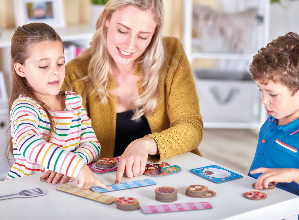 Woman and two children playing a board game together in a cozy room.