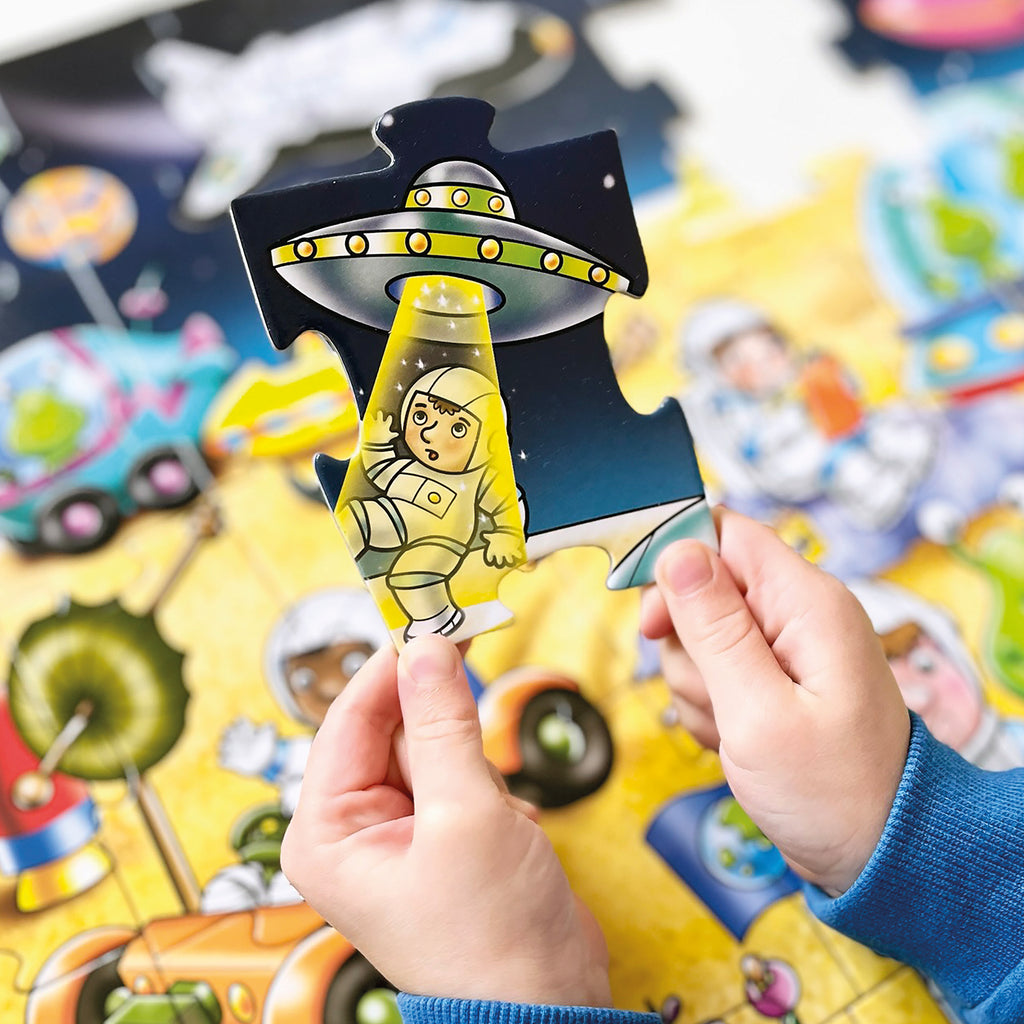 Child holding a toy with a green alien and UFO design against a colorful background