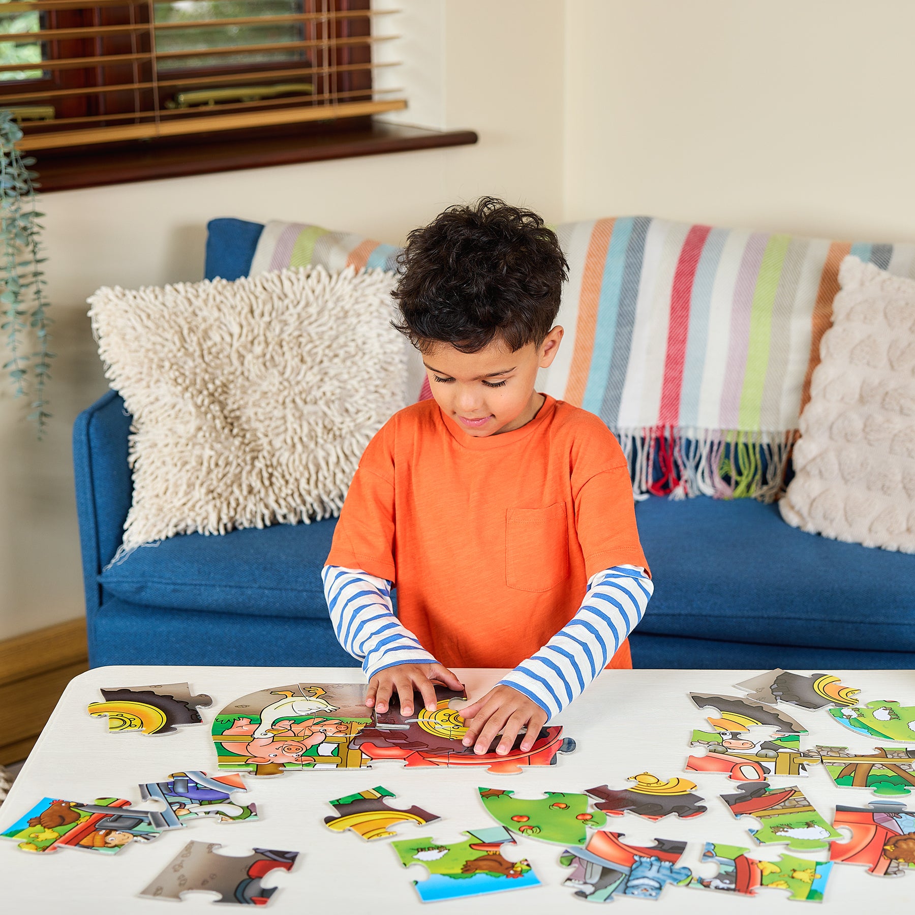 Child playing with a puzzle on a table in a living room.