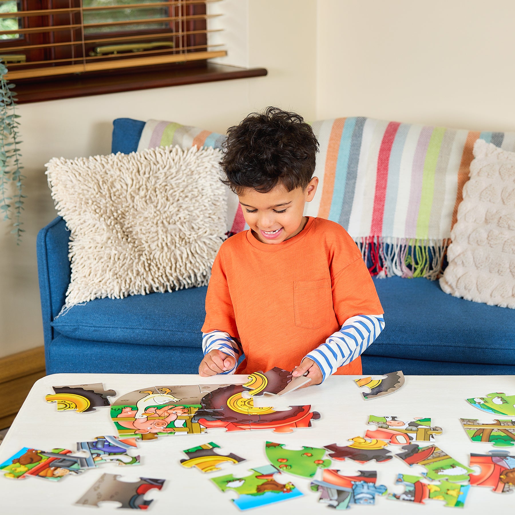 Child playing with puzzle pieces on a table in a living room.