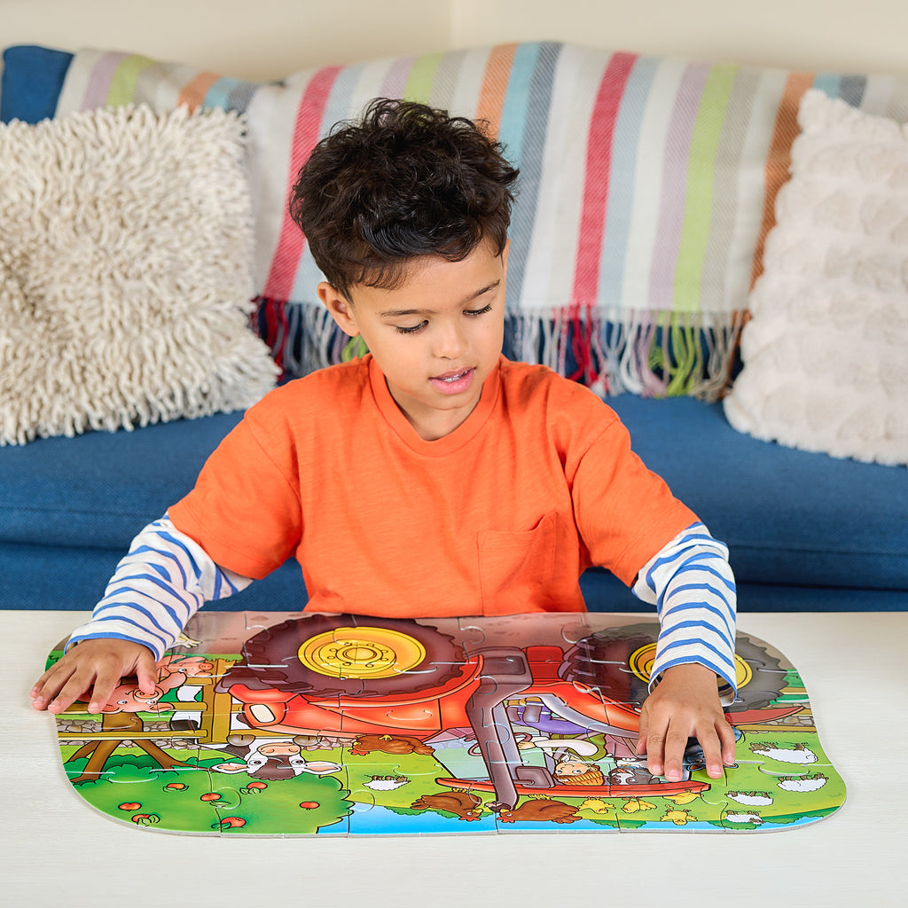 Child playing with a colorful farm-themed puzzle on a table.