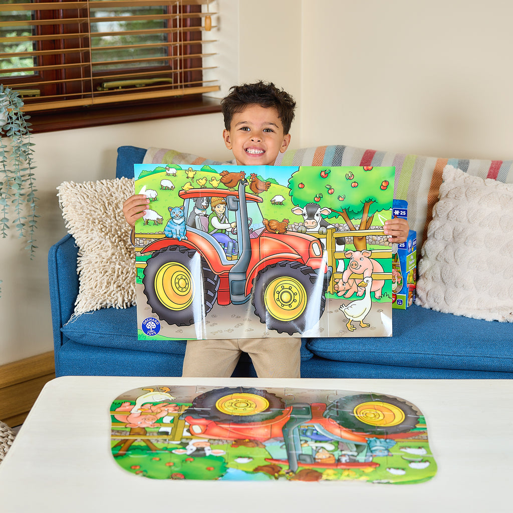 Child holding a colorful children's book with a tractor on a couch
