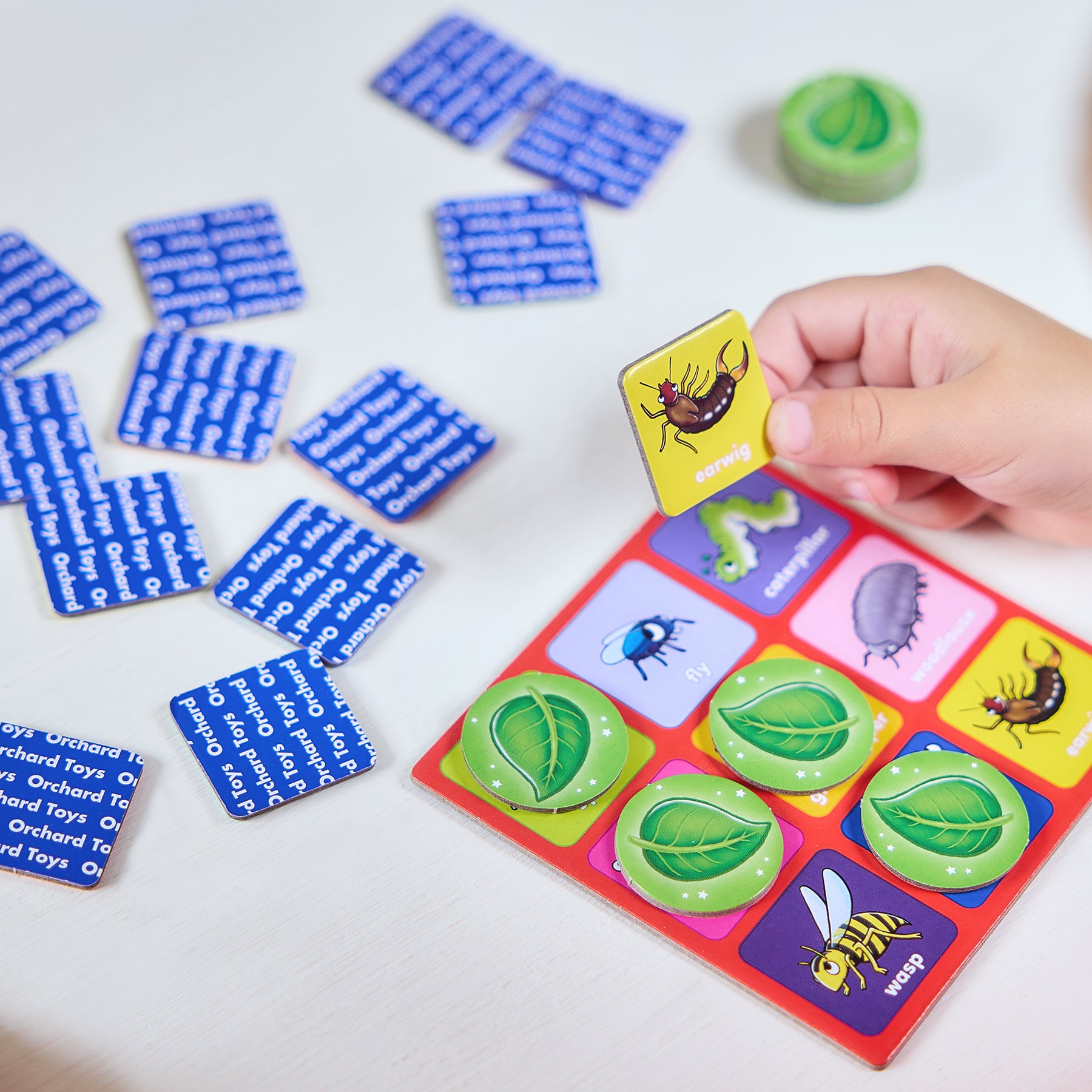 Children's educational game with colorful cards and a hand holding a card.